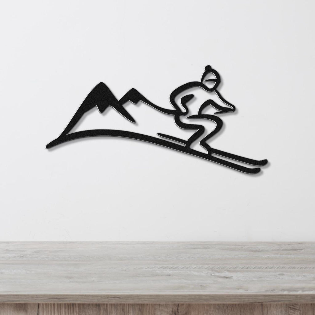 Black metal wall art featuring a dynamic skier silhouette gliding over mountain peaks, mounted on a white wall above a wooden surface.
