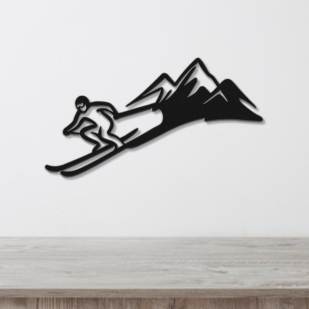 Black metal wall art featuring a skier silhouette in motion with mountain peaks, mounted on a white wall above a wooden surface.