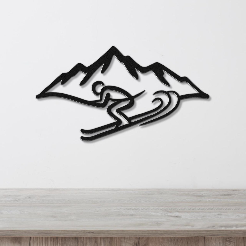 Black metal wall art featuring a skier silhouette in motion with mountain peaks, mounted on a white wall above a wooden surface.
