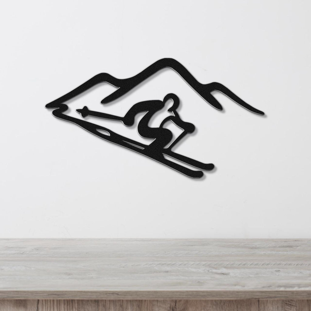 Black metal wall art featuring a skier silhouette and mountain cutout, mounted on a white wall above a wooden surface.
