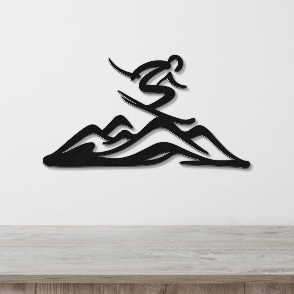 Black metal wall art featuring a skier silhouette above layered mountain cutouts, mounted on a white wall above a light wood counter.