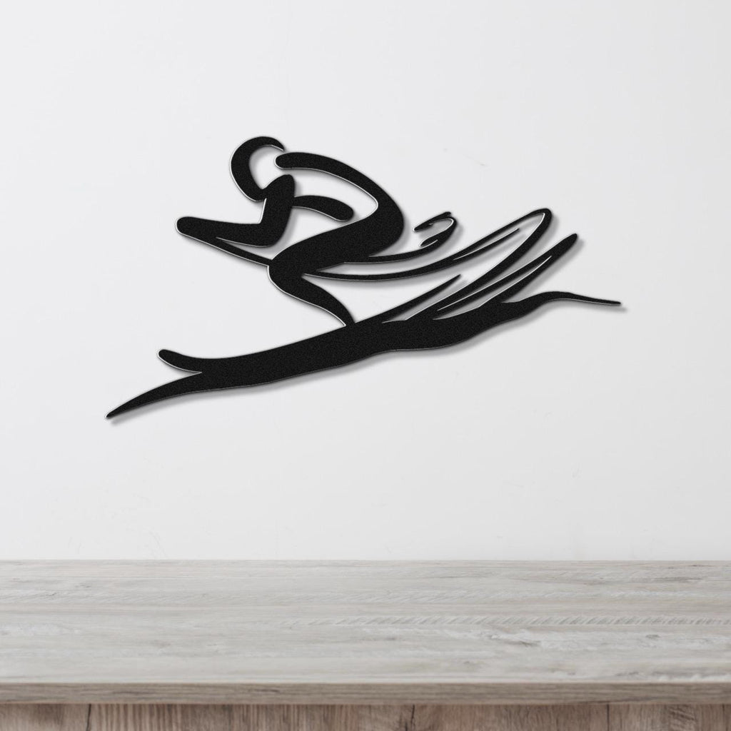 Black metal wall art of a skier in motion, with flowing cutout lines, mounted on a white wall above a wooden surface.