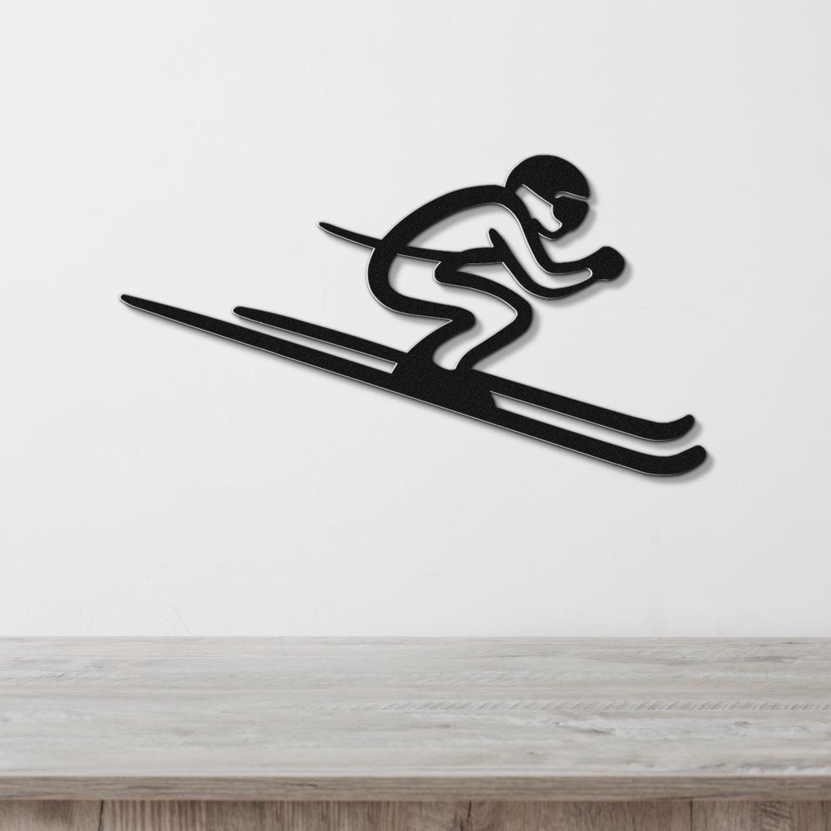 Black metal wall art of a skier silhouette with motion lines, mounted on a white wall above a wooden surface.