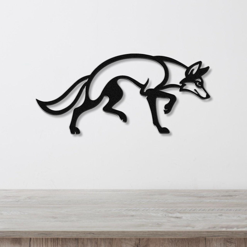 Black metal coyote wall art with a sleek silhouette design, mounted on a white wall above a light wood surface.