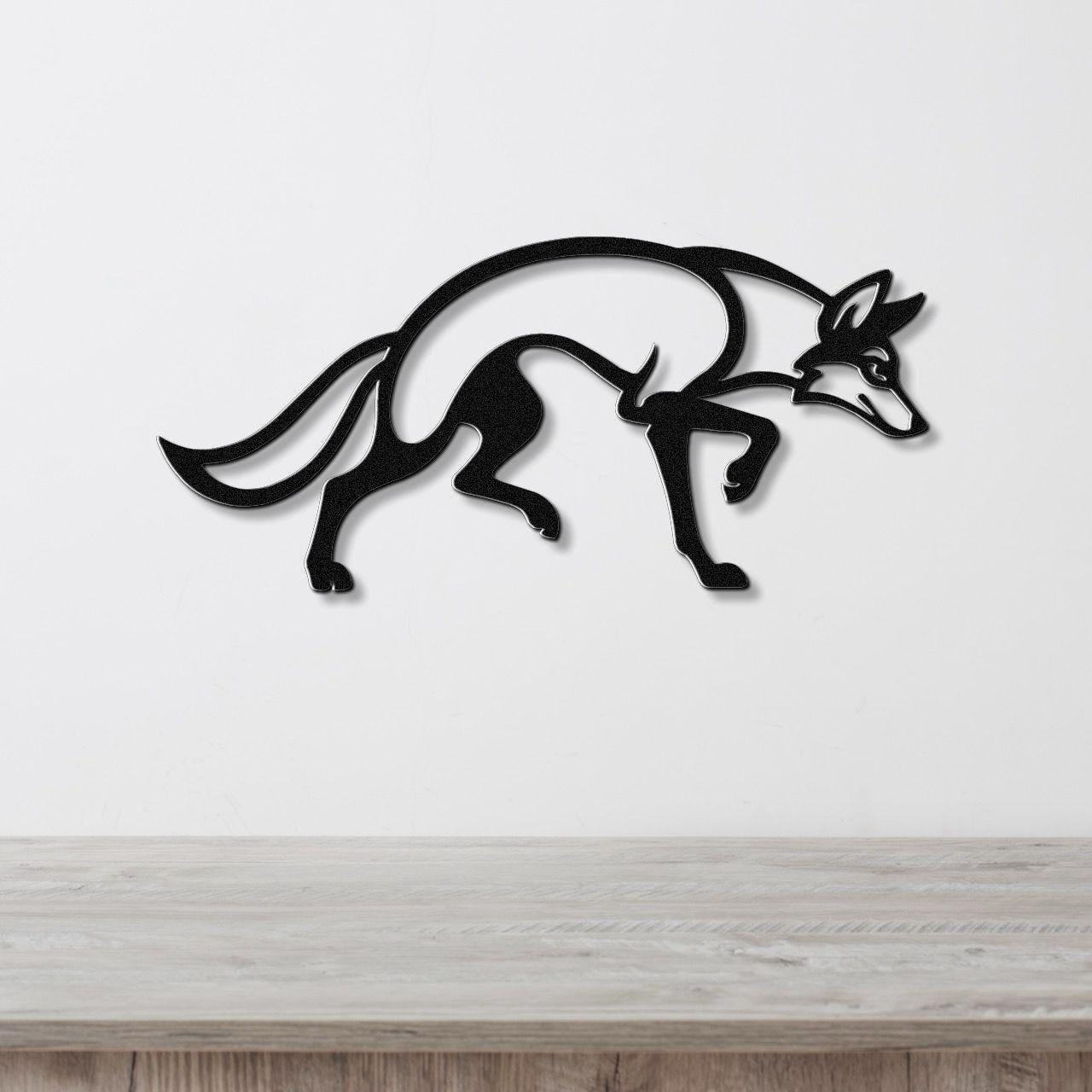 Black metal coyote wall art with a sleek silhouette design, mounted on a white wall above a light wood surface.