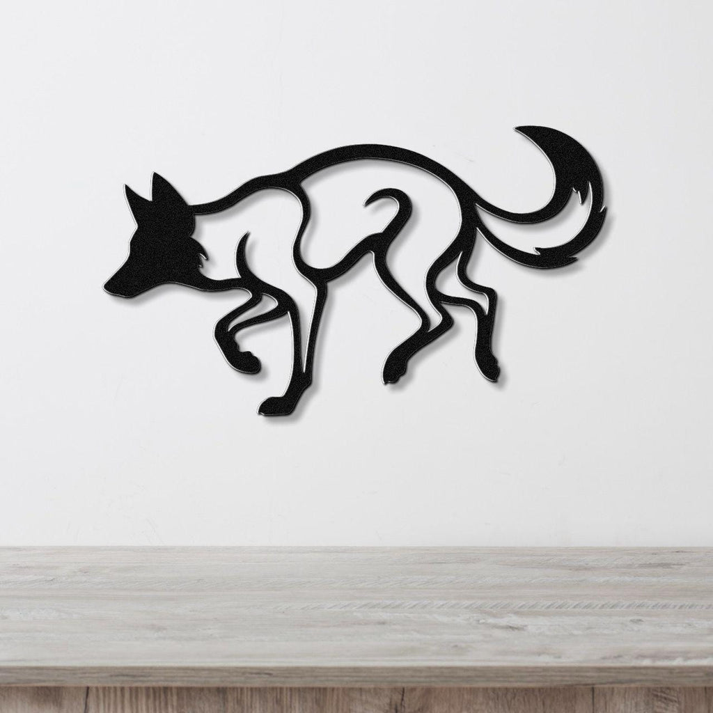 Black metal coyote wall art with a bold silhouette and internal cutout details, mounted on a white wall above a light wood surface.