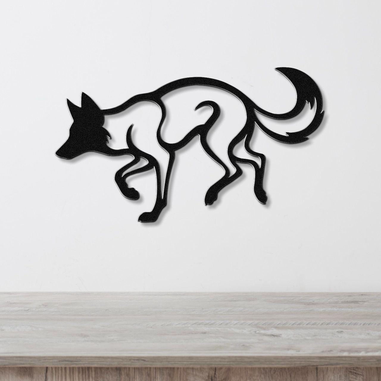 Black metal coyote wall art with a bold silhouette and internal cutout details, mounted on a white wall above a light wood surface.