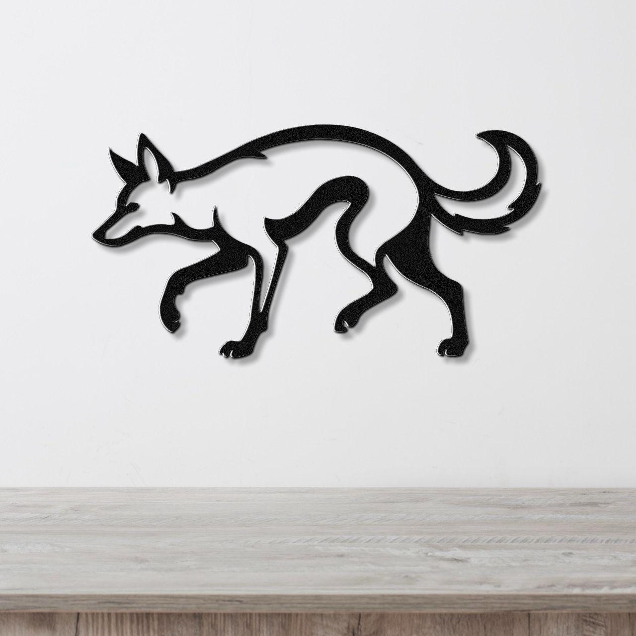 Black metal coyote wall art with a minimalist silhouette design, mounted on a white wall above a light wood countertop.
