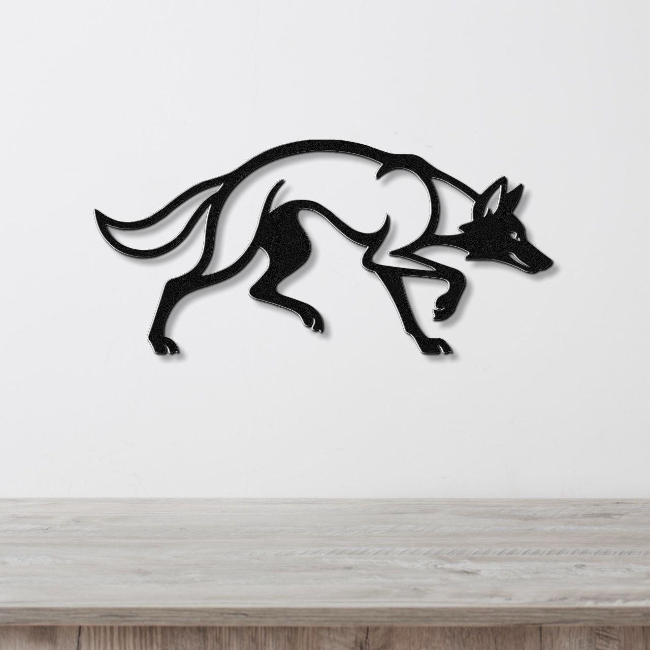 Black metal coyote wall art with motion-line cutouts, mounted on a white wall above a light wood counter.