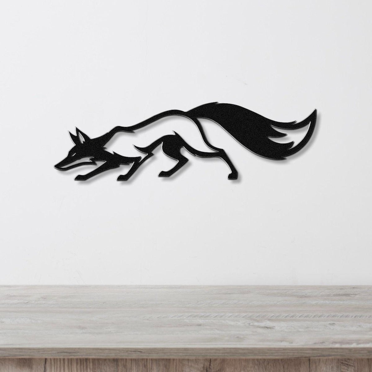 Black metal fox wall art with a dynamic running silhouette, mounted on a white wall above a light wood surface.