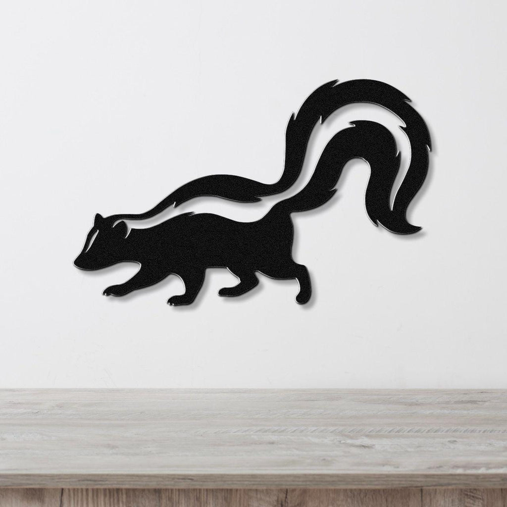 Black metal skunk wall art with a white stripe cutout, mounted on a white wall above a wooden surface.