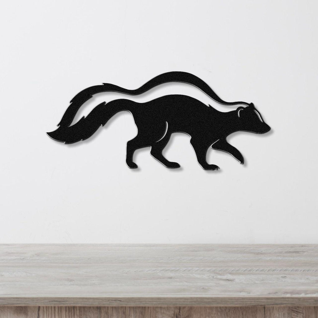 Black metal skunk wall art silhouette with a curved tail, mounted on a white wall above a light wood surface.