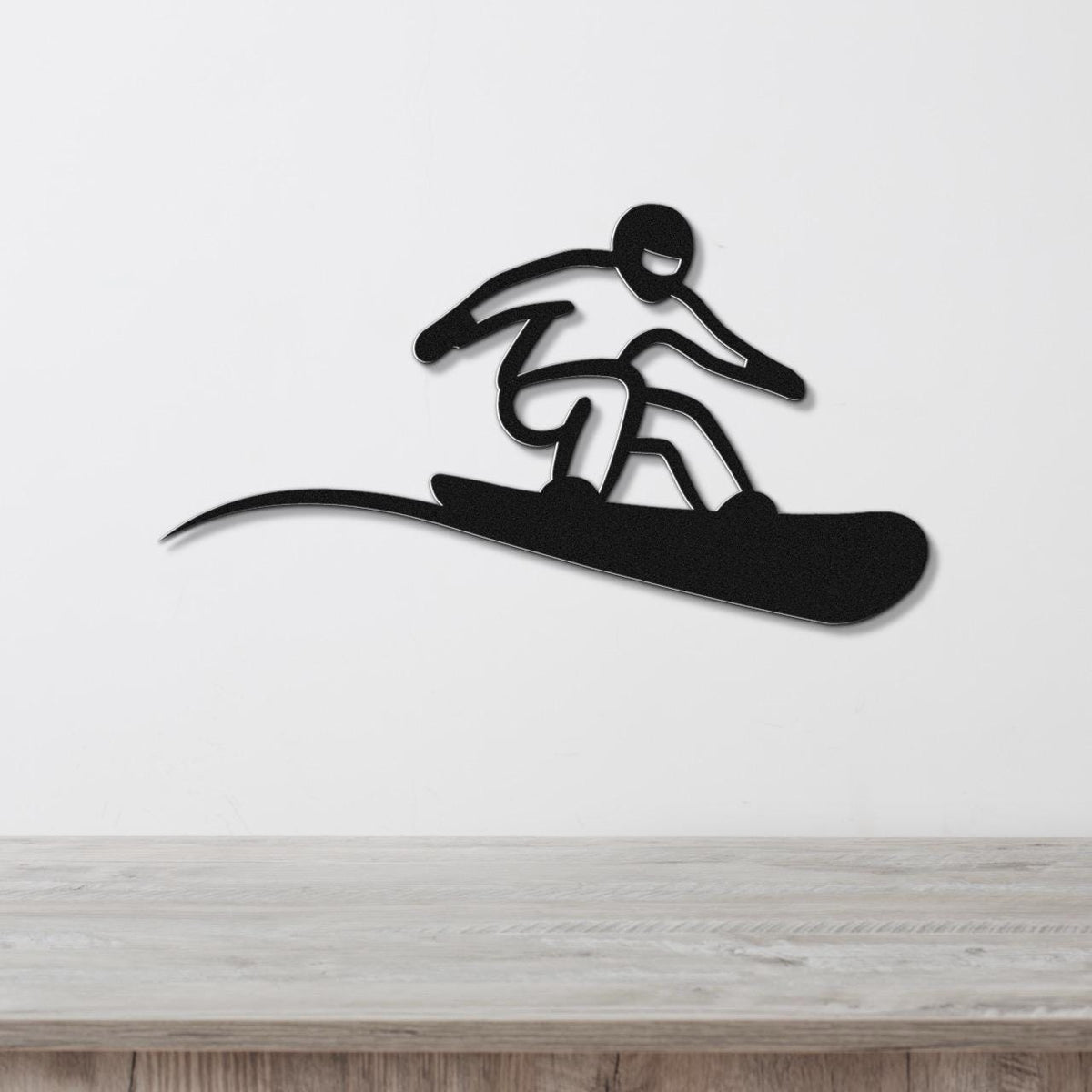 Black metal snowboarder wall art with a bold silhouette and motion-line cutout, mounted on a white wall above a light wood counter.