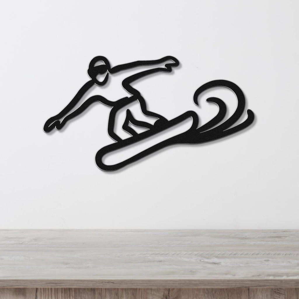 Black metal wall art of a snowboarder in motion, featuring a silhouette cutout with dynamic lines, mounted on a white wall above a wooden surface.