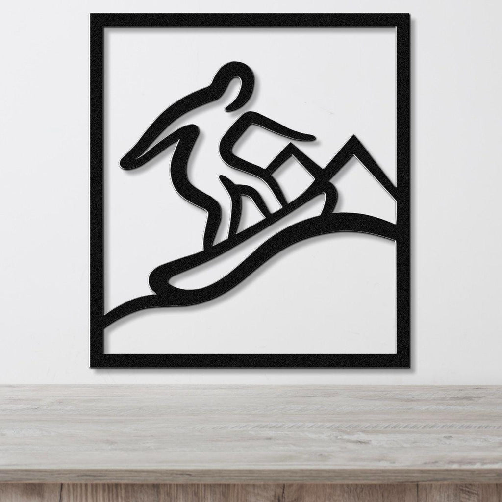 Black metal wall art with a silhouette of a snowboarder in motion, mounted on a white wall above a wooden surface.