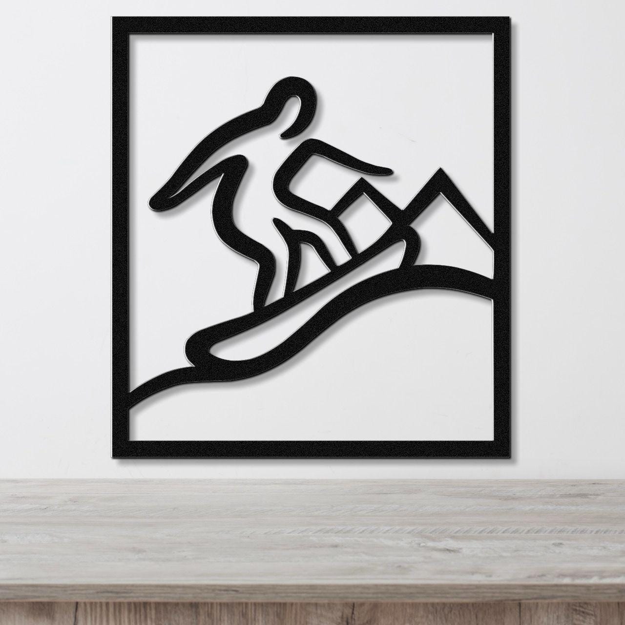 Black metal wall art with a silhouette of a snowboarder in motion, mounted on a white wall above a wooden surface.