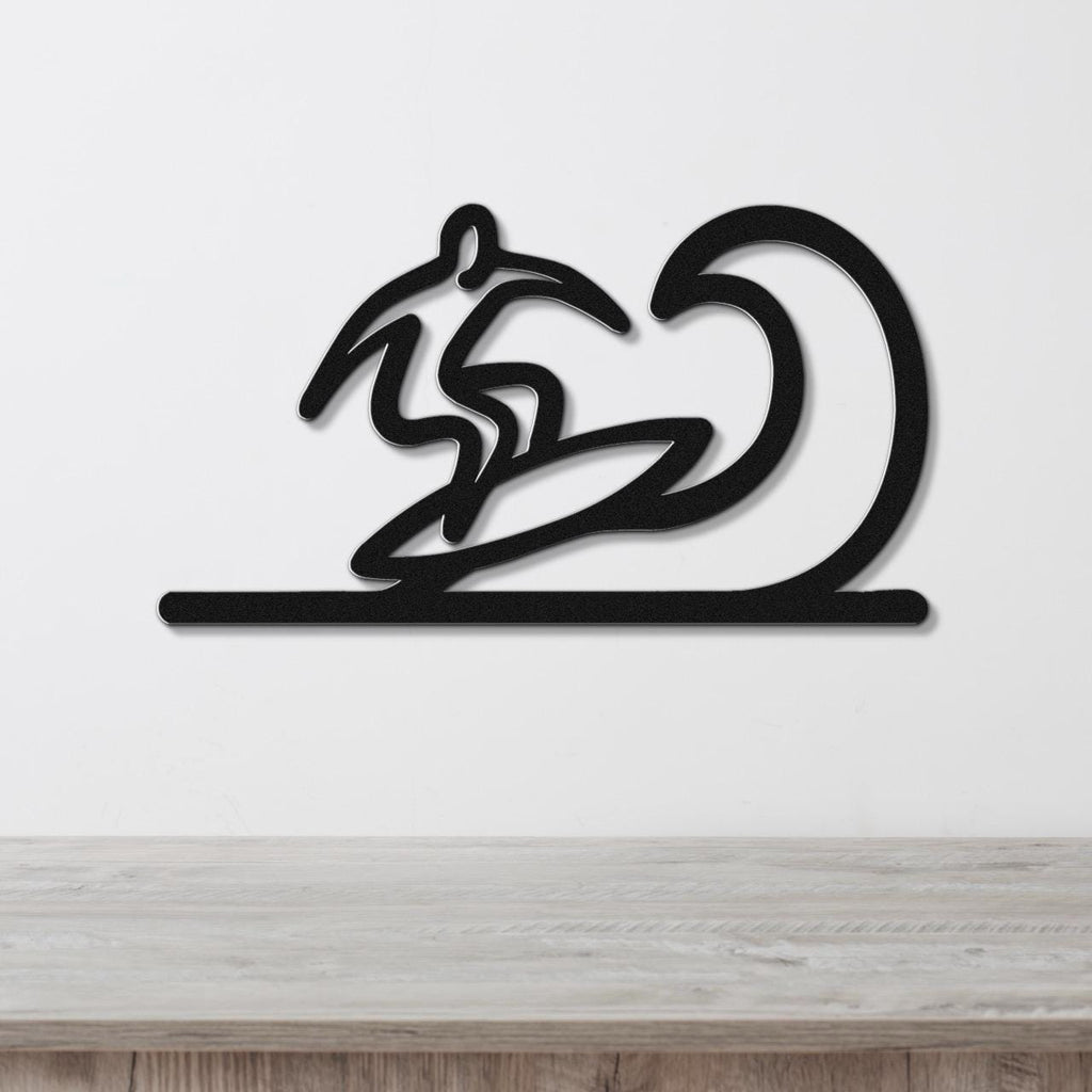 Black metal wall art featuring a surfer silhouette riding a wave, mounted on a white wall above a wooden surface.