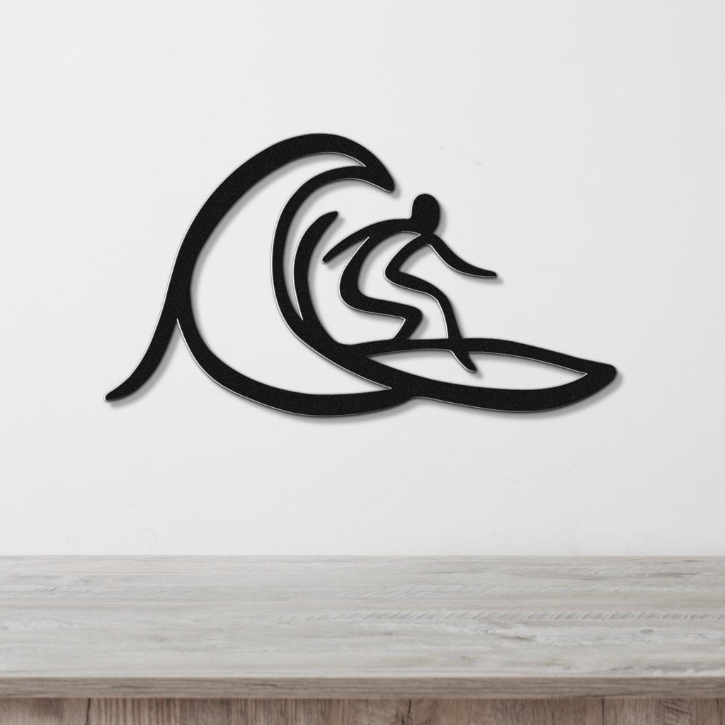 Black metal wall art featuring a surfer silhouette riding a wave, mounted on a white wall above a wooden surface.