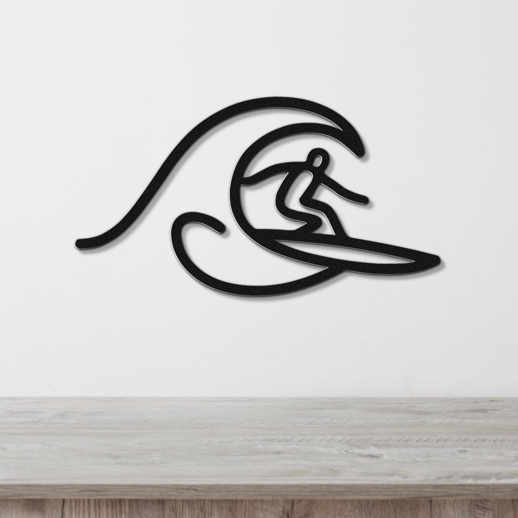 Black metal wall art featuring a surfer silhouette riding a wave, mounted on a white wall above a wooden surface.