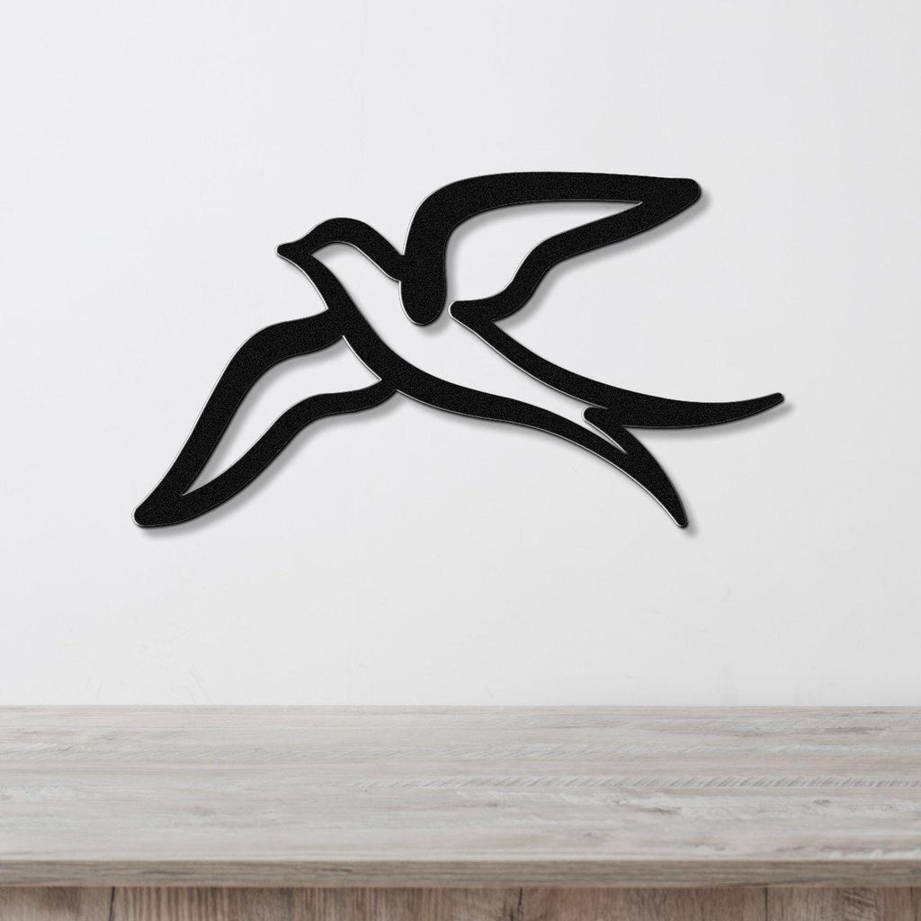 Black metal swallow bird wall art with a graceful silhouette and open-wing cutout, mounted on a white wall above a light wood counter.
