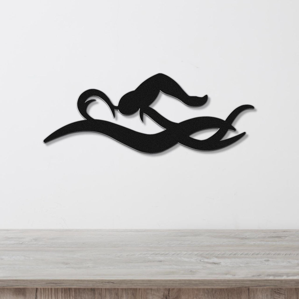 Black metal wall art of a swimmer in motion, with fluid cutout lines, mounted on a white wall above a wooden surface.