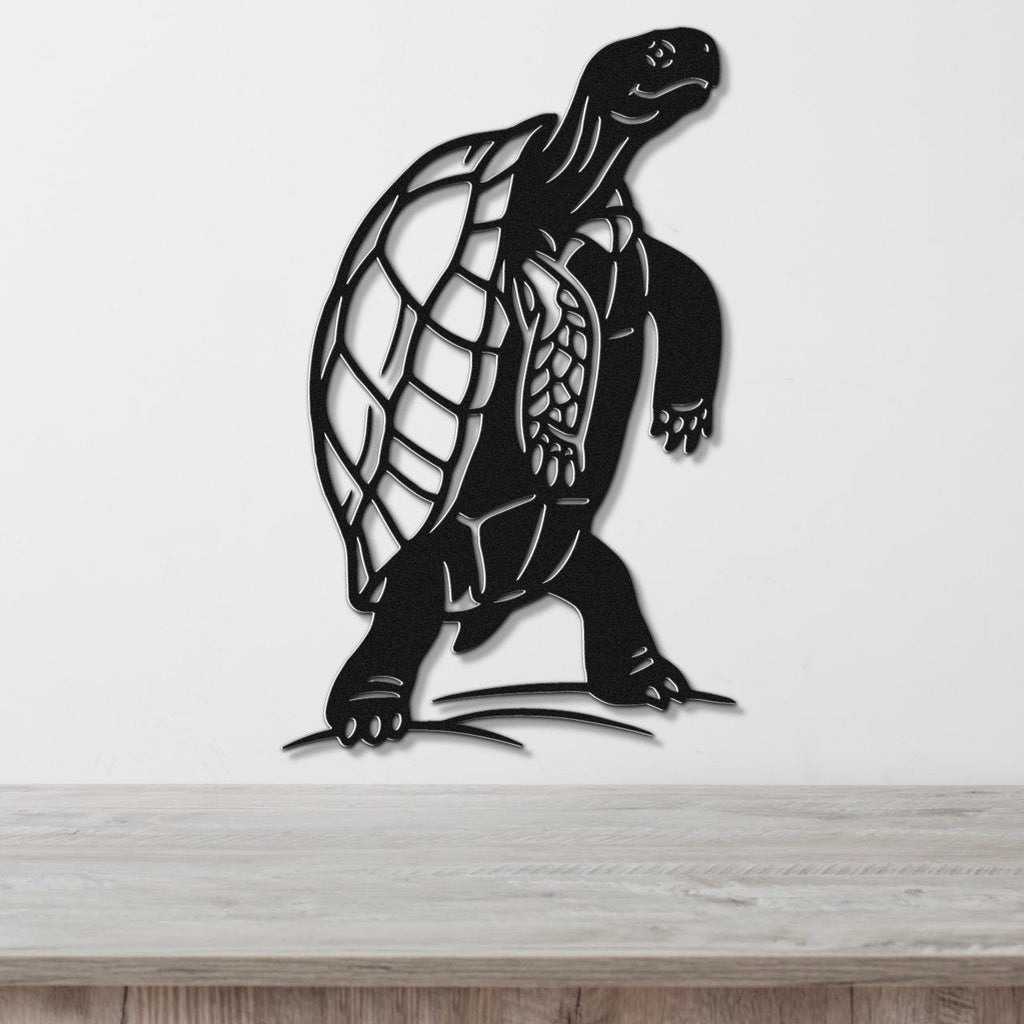 Black metal tortoise wall art with detailed shell and limb cutouts, mounted on a white wall above a light wood surface.