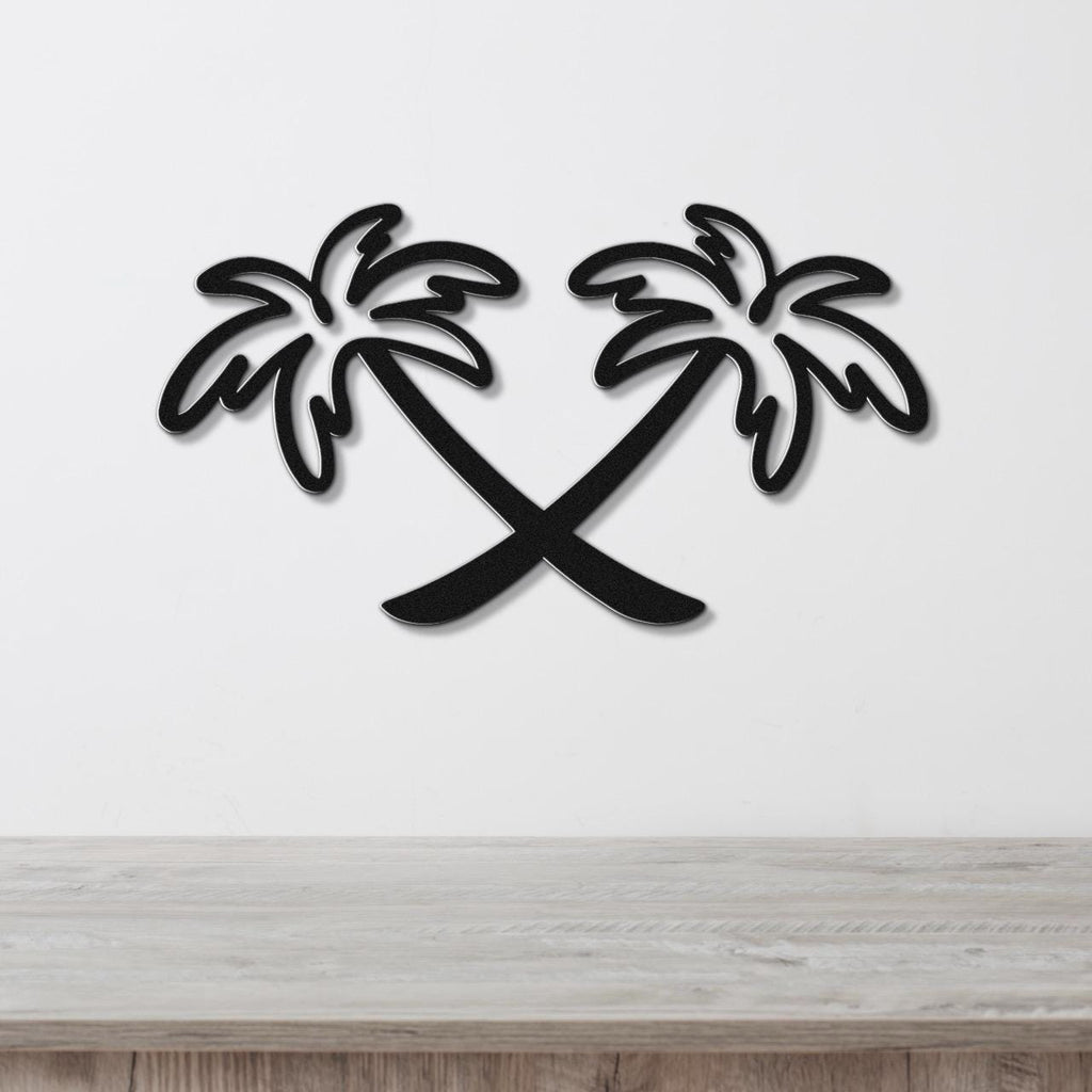 Black metal wall art featuring two crossed palm trees in a silhouette style, mounted on a white wall above a light wood surface.
