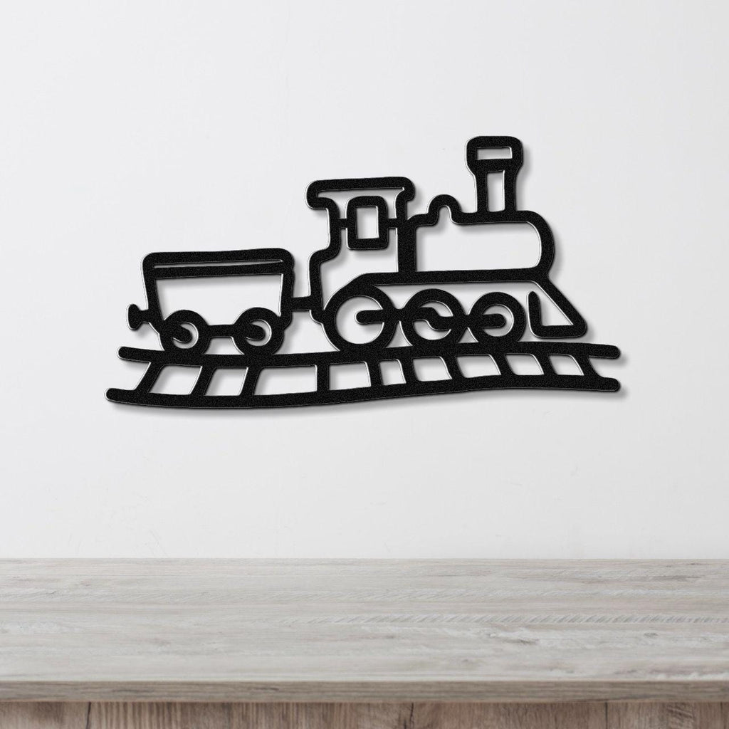 Black metal train wall art with a silhouette design of a locomotive and car on tracks, mounted on a white wall above a wooden surface.