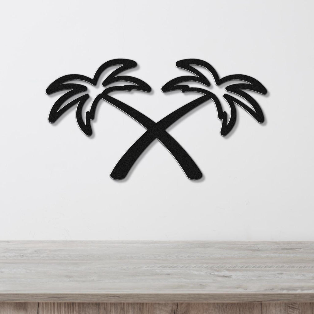 Black metal wall art featuring two crossed palm trees in a silhouette style, mounted on a white wall above a light wood surface.