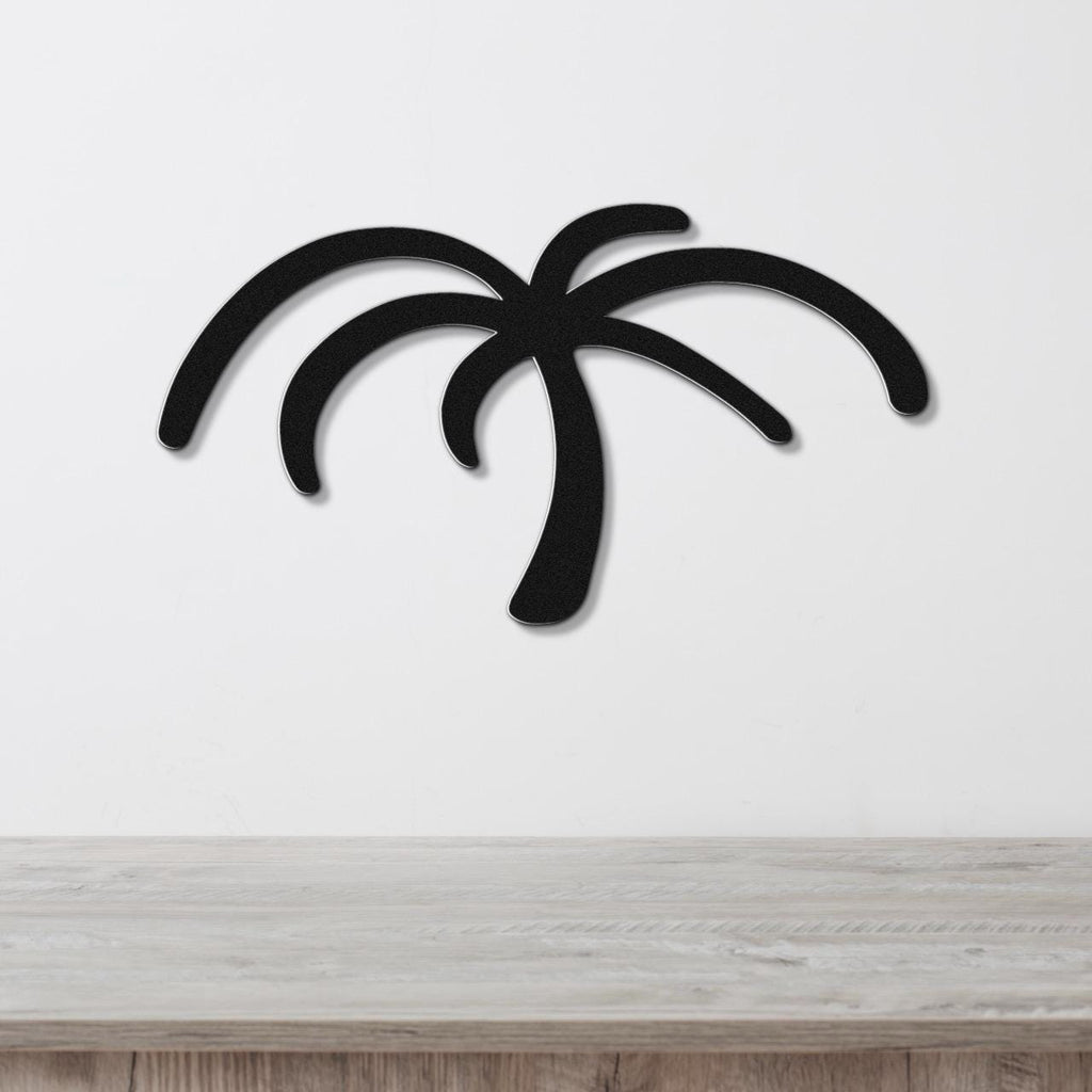 Black metal palm tree wall art with curved frond cutouts, mounted on a white wall above a light wood surface.