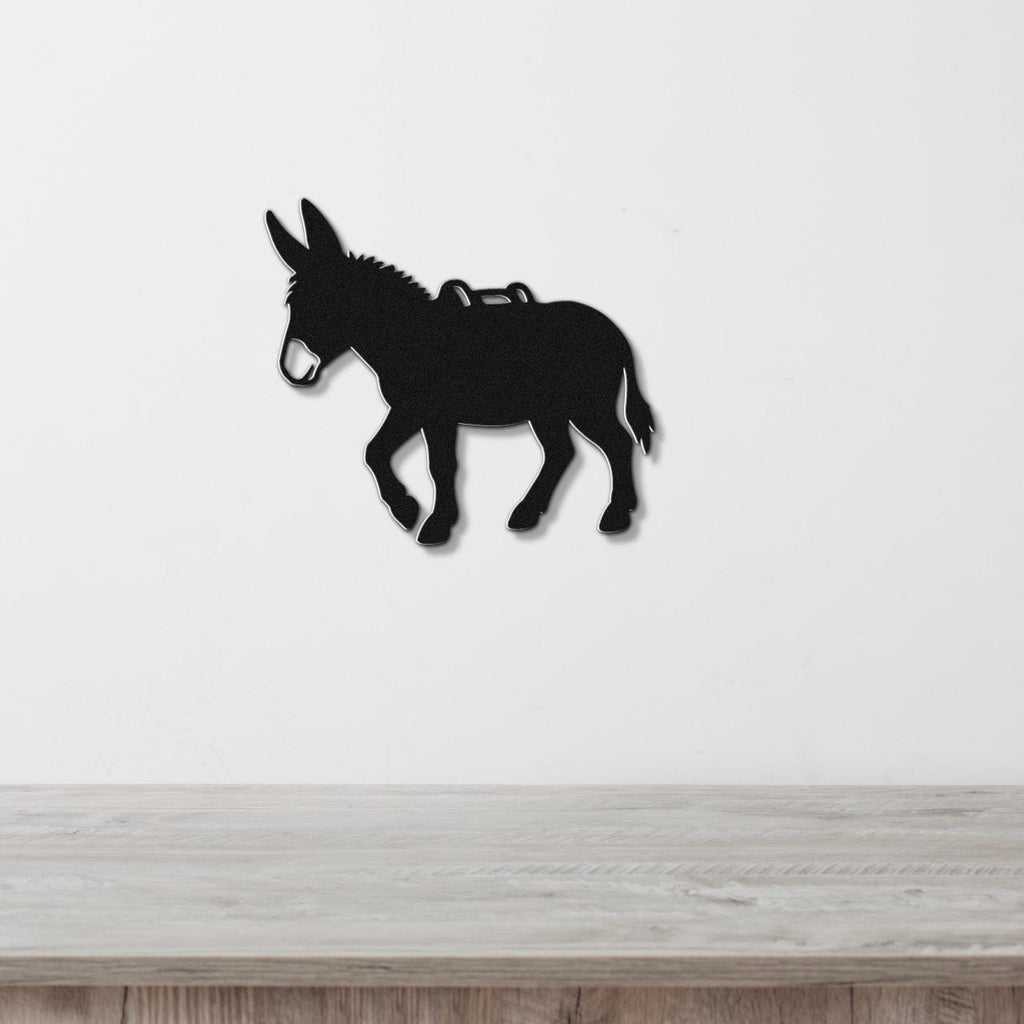 Black metal burro silhouette wall art with saddle cutout, mounted on a white wall above a light wood counter.