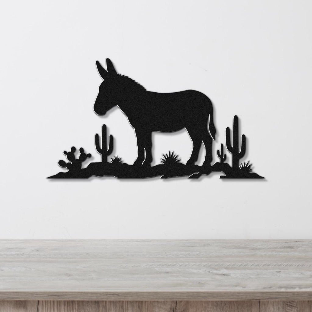 Black metal wall sculpture of a burro silhouette with cacti, mounted on a white wall above a wooden surface.