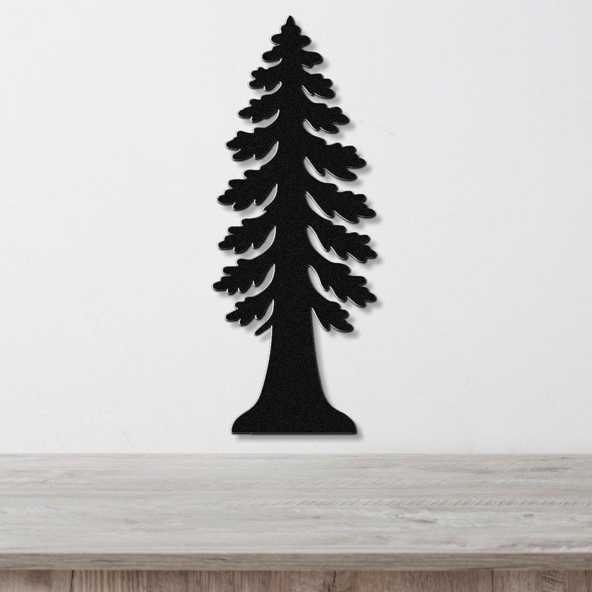 Black metal wall art cutout of a redwood tree with layered branches, mounted on a white wall above a light wood countertop.