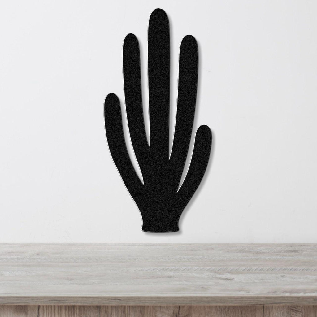 Black metal wall art cutout of an organ pipe cactus with five vertical arms, mounted on a white wall above a light wood surface.