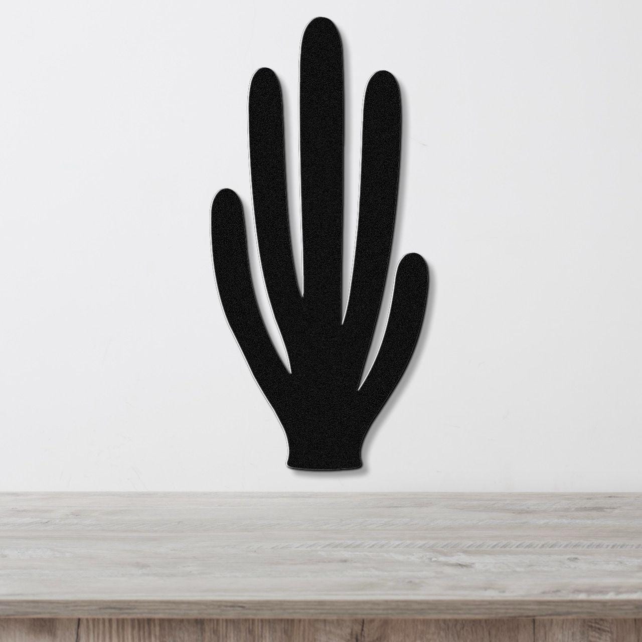 Black metal wall art cutout of an organ pipe cactus with five vertical arms, mounted on a white wall above a light wood surface.