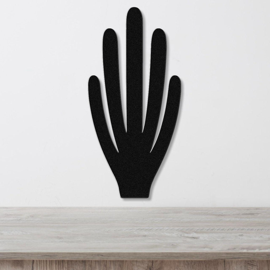 Black metal wall art in the shape of a hand with five fingers, mounted on a white wall above a wooden surface.
