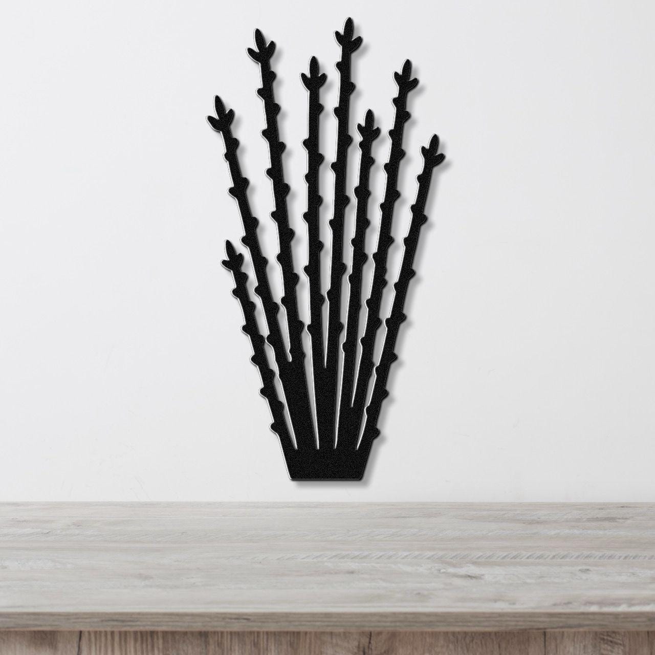 Black metal ocotillo wall art with spiky branch cutouts, mounted on a white wall above a light wood counter.