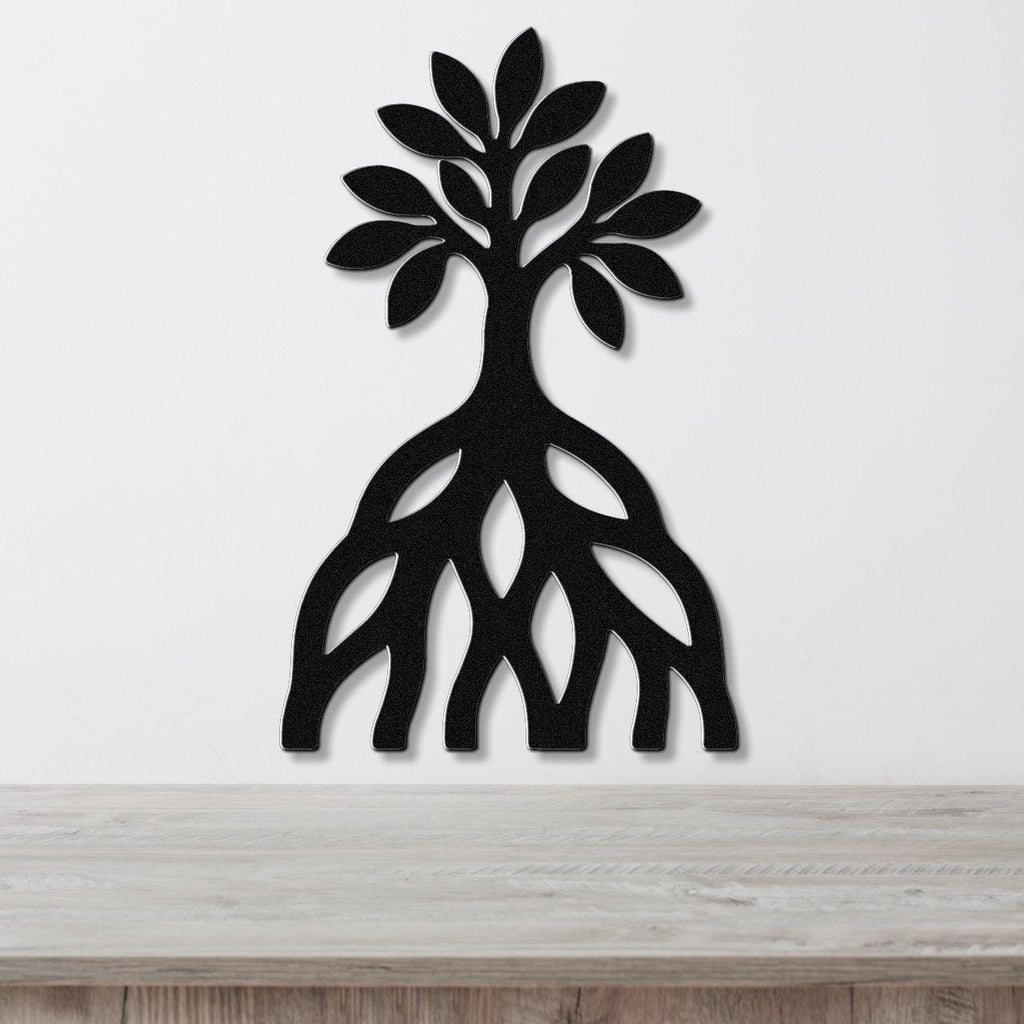 Black metal wall art silhouette of a mangrove tree with visible root cutouts, mounted on a white wall above a wooden surface.