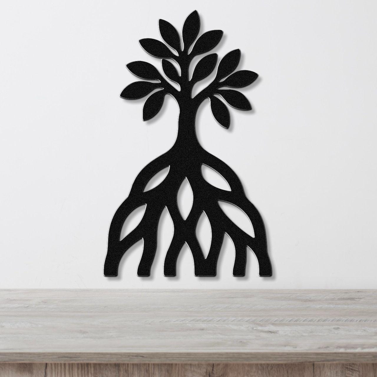 Black metal wall art silhouette of a mangrove tree with visible root cutouts, mounted on a white wall above a wooden surface.