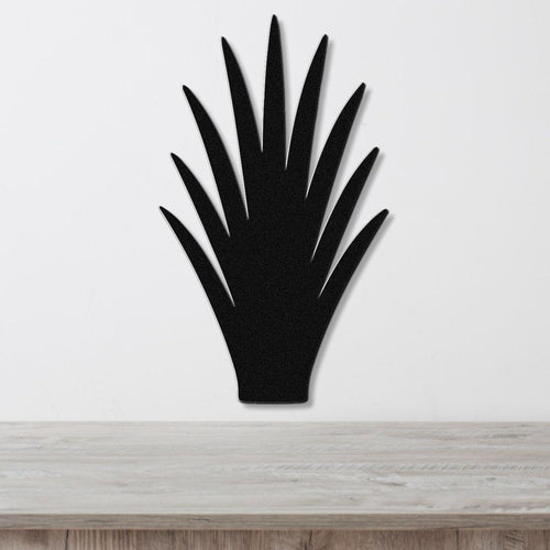 Black metal wall art in the silhouette of a spiky desert plant, mounted on a white wall above a light wood surface.