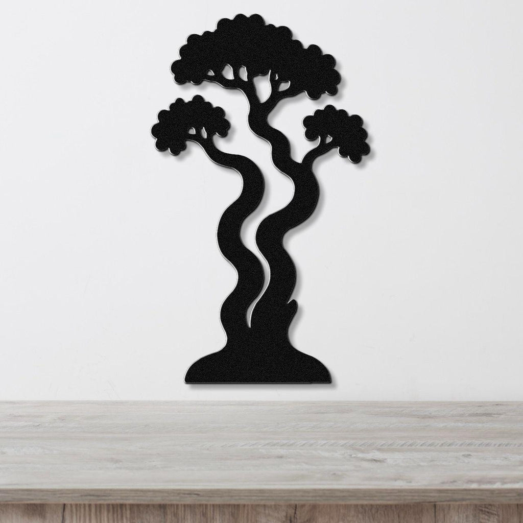 Black metal wall art in a bonsai tree silhouette with wavy trunk and layered branches, mounted on a white wall above a light wood surface.