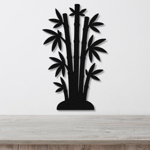 Black metal wall art cutout of a bamboo cluster with multiple stalks and leaves, mounted on a white wall above a light wood surface.