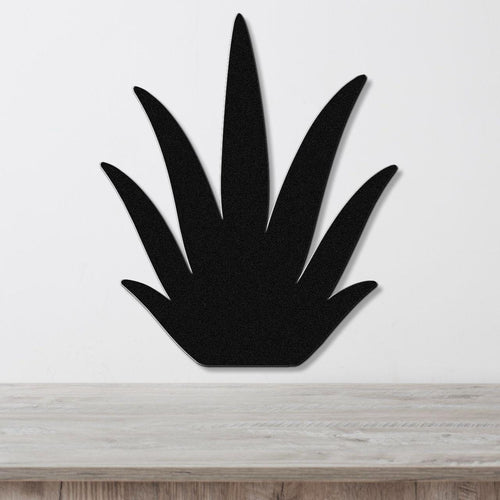 Black metal agave wall art with pointed leaf cutouts, mounted on a white wall above a light wood surface.