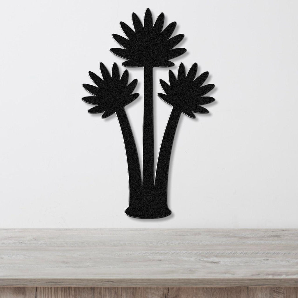 Black metal wall art cutout of three fan palm trees, mounted on a white wall above a light wood countertop.