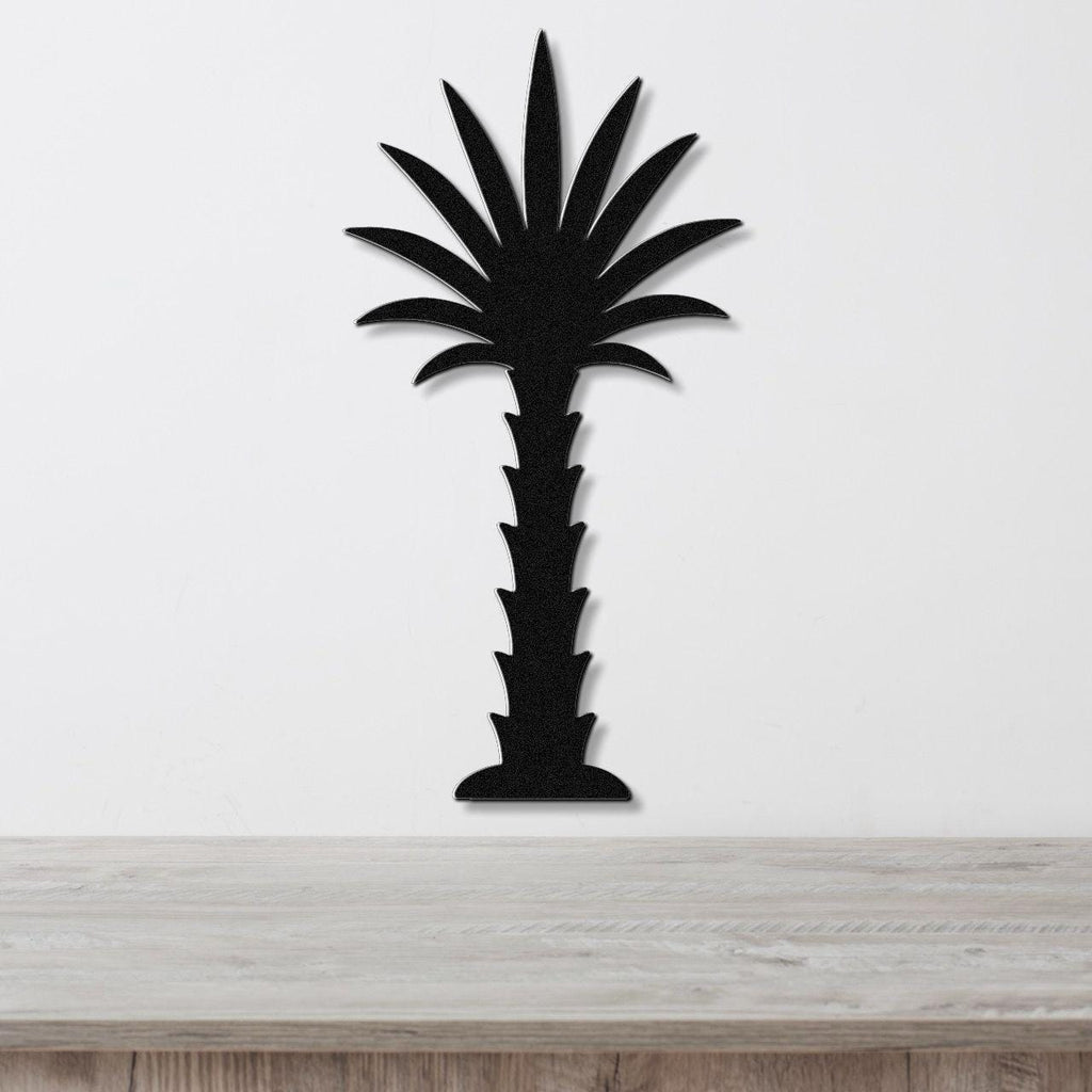 Black metal palm tree wall art with a silhouette design, mounted on a white wall above a wooden surface.