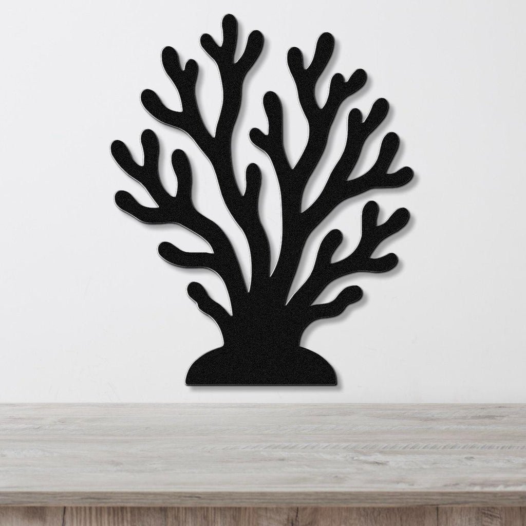 Black metal coral wall art with branching cutouts, mounted on a white wall above a light wood countertop.