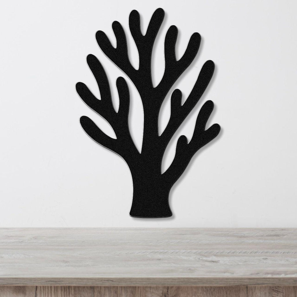 Black metal coral wall art with branching cutouts, mounted on a white wall above a light wood counter.