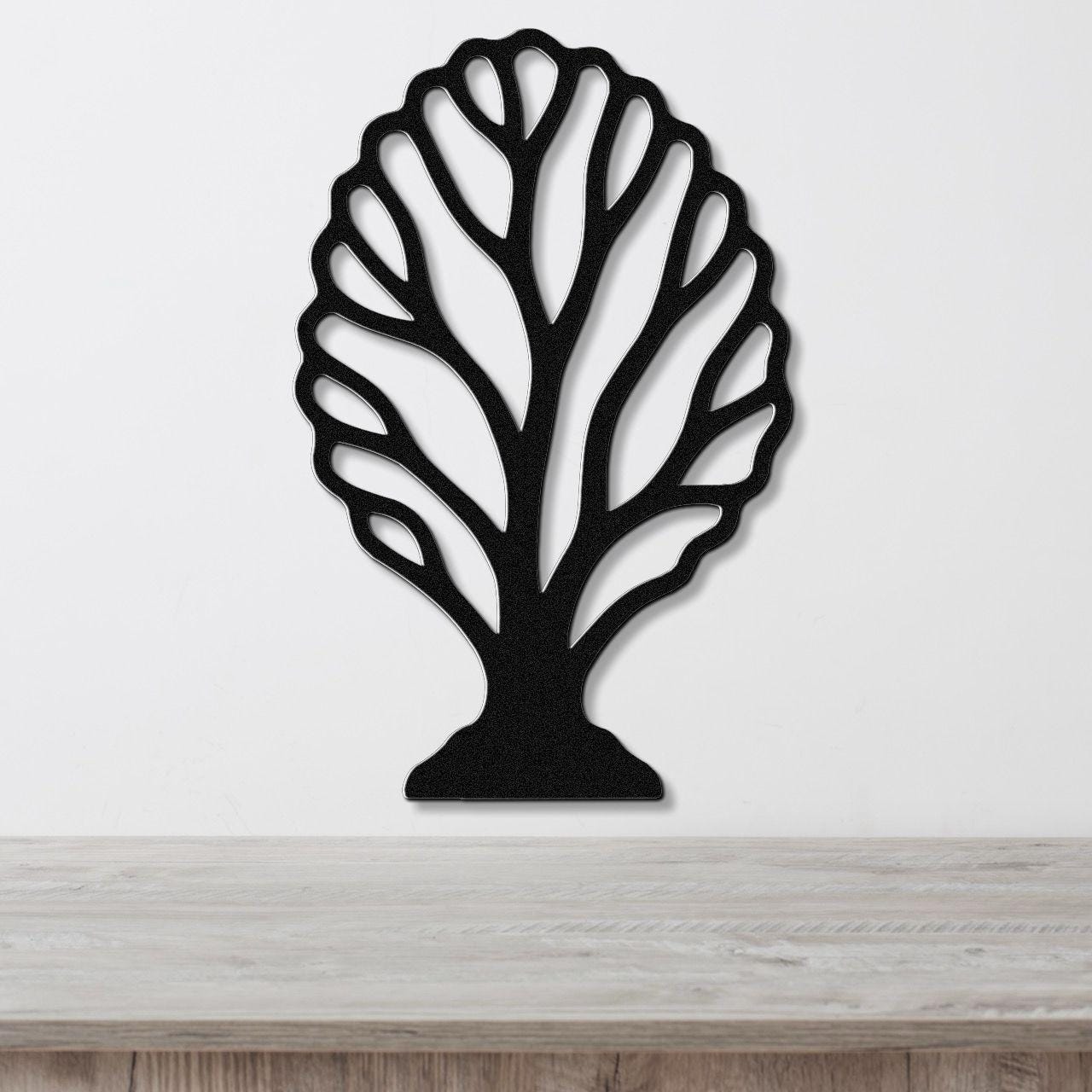 Black metal wall art in a fan coral silhouette with intricate branch cutouts, mounted on a white wall above a light wood surface.