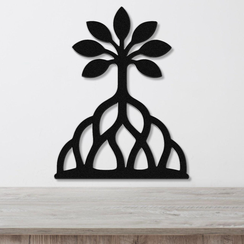 Black metal wall art in the shape of a tree with leafy top and exposed root system, mounted on a white wall above a wooden surface.