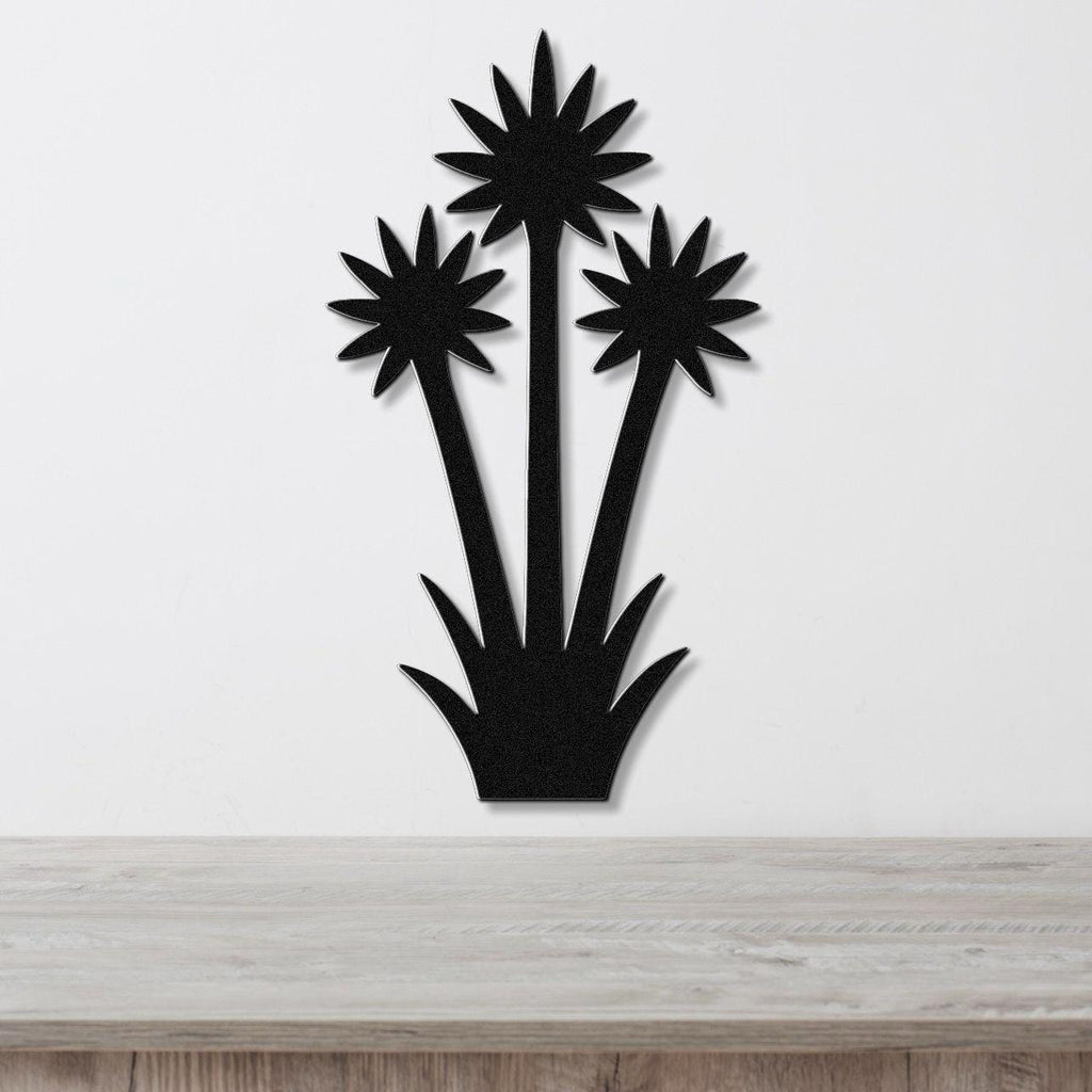 Black metal wall art cutout of three yucca plants with starburst tops, mounted on a white wall above a light wood surface.